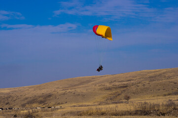 Paragliding. A man flies on a parachute against the blue sky.