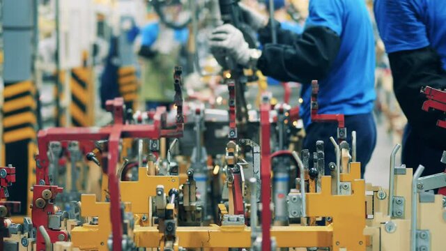 Mechanic moving a ready-made auto part ona car factory facility. Modern production of cars. Close up