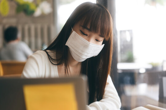 Young Adult Asian Female With Protective Face Mask For Virus Covid 19 Work And Study At Cafe On Day.