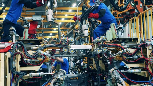 Car body workers welding car body at a car manufacturing facility.