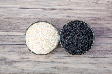 Black and white sesame in bowl on wood table background. White sesame and black sesame seed in bowls.