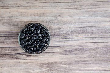 Pile of raw Black Beans in a bowl. black beans on wood background. Dry black beans in dark wooden bowl.