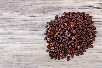 Coffee beans on wooden background. Pile of coffee. Coffee beans on a wooden background. Top view. Copy space.