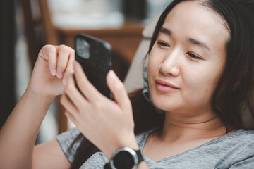 Closeup image of a young smart asian female holding and using smart phone.