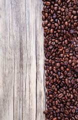Coffee beans on wooden background. Pile of coffee. Coffee beans on a wooden background. Top view. Copy space.
