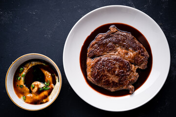 Top down view on delicious meat dinner in dark round plate with copy space over wooden table