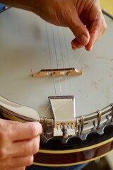 Close up of hands changing string and tuning a banjo