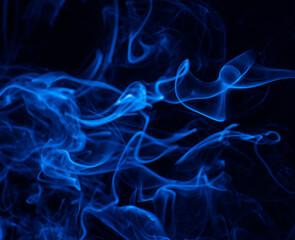 Conceptual image of blue color smoke isolated on dark black background.