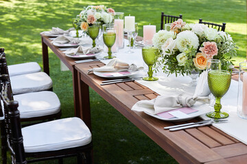 dinner tables with white cloth, served with porcelain and green glasses. Georgeous wedding table decorated with flowers