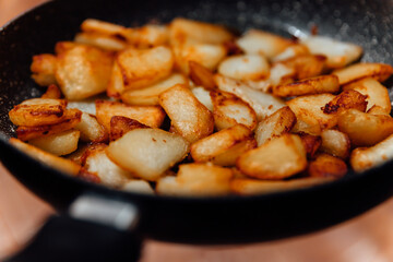 Fried pieces of potato in the pan. Harmful food close up.