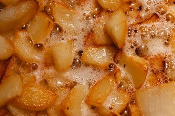 Chunks of potatoes are fried in boiling oil. Close-up photo of cooking junk food.