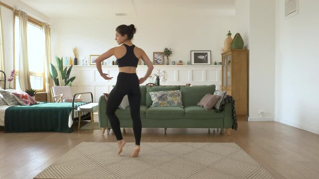 A young Indian Female Ballerina trains at home, Does a Spinning exercise, Bright Cozy Room, Dressed in a Black Top and Leggings. Sports Concept Healthy Life