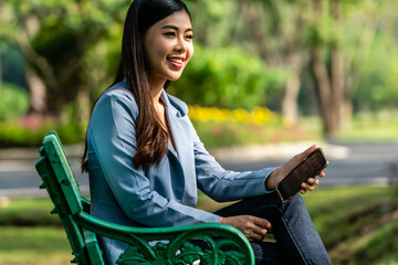 Asian working woman smiling  sitting on bench talking with someone in the public park