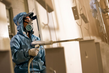 Asian worker wearing gas mask and clothing working in spray painting workshop