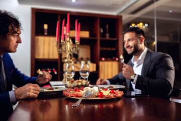 Two elegantly dressed men having dinner