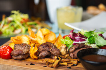 Meat, shish kebab, grilled, barbecue with baked potatoes and vegetables on a wooden plate on the table