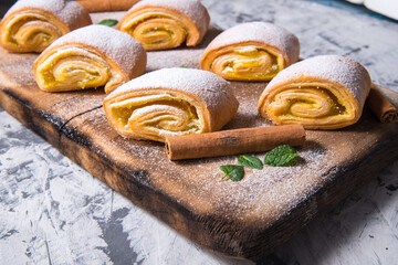 Baking strudel,rolls powdered with mint leaves tangerines,cinnamon sticks on a black and white background,on a wooden Board with a space for text,side view