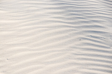 Beautiful sand`s background with graphics waves, shadows and lights. Shadows and patterns on the sand of dune. Background, sand, light, beige, wave, reflect, shadow, summer.