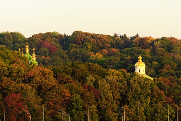 Astonishing  morning autumn landscape view of famous Kyiv's hills against blue sky. The domes Saint George's Cathedral and ancient Michael's Cathedral of Vydubychi Monastery over the old trees. Kyiv