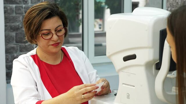 Optician doctor working with the refractometer machine. Eye exam for young woman at optical store. Consultation with an optometrist after testing.