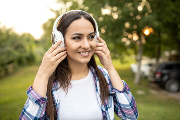 Pretty young woman listening to music outdoors