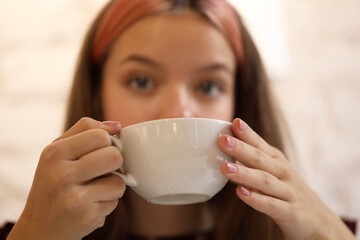 girl drinking coffee or tea, the background is blurred