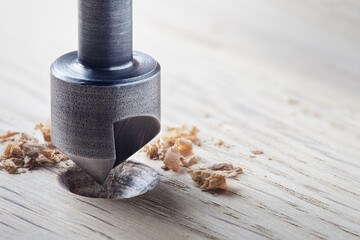Countersink drill bit make sink in hole for screw in wooden plank.