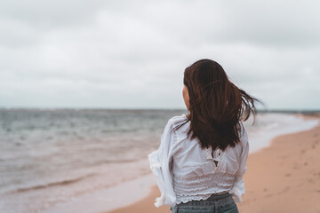 Young woman feeling lonely and sad looking at the sea on a cloudy day