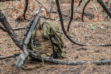 scout rifle lies on a backpack in the forest, survival rifle, soft focus