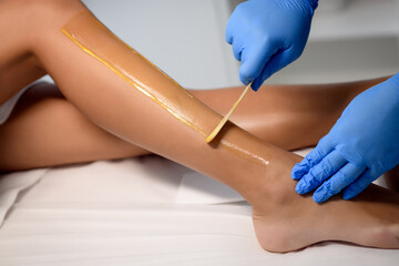 Close up waxing in by a beautician in a spa center - obrazy, fototapety, plakaty