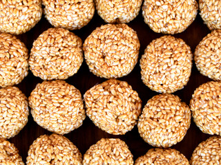 White sesame seed balls made with heated jiggery against wooden background
