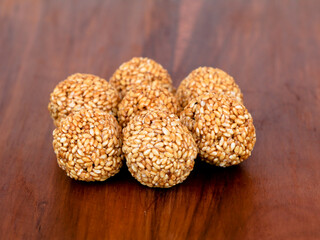 White sesame seed balls made with heated jiggery against wooden background