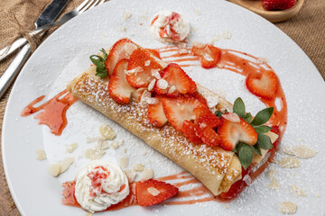 Thin hot pancakes with cottage cheese and strawberries, top view. Healthy traditional breakfast concept.