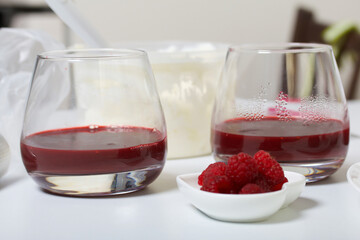 Cooking cream cheese dessert with raspberry jelly. The ingredients are laid out on the table surface. Decorated with cookies, raspberries and mint.