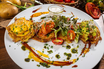 Potato cakes with topping: bacon and poached egg. Vegetable fritters, pancakes