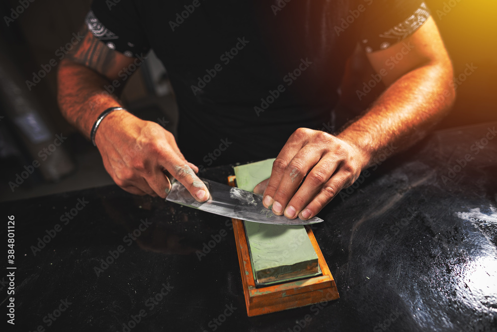 Wall mural man's hands sharpening knife