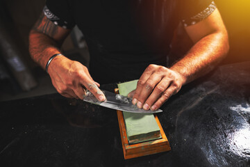 Man's hands sharpening knife - obrazy, fototapety, plakaty