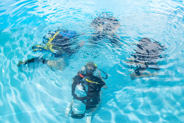A diving instructor teaches a group of people how to behave underwater with scuba diving