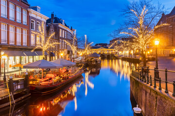 Obraz premium The Dutch Oude Rijn canal with bridge, historic buildings and christmas lights in the city center of Leiden