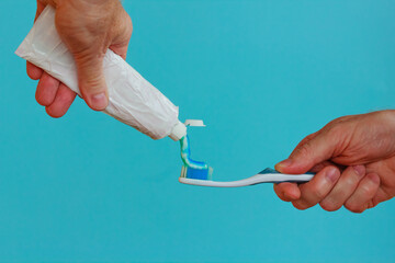 a man crashes the tube of toothpaste /A man crushes the toothpaste with his hand to brush your teeth with a toothbrush