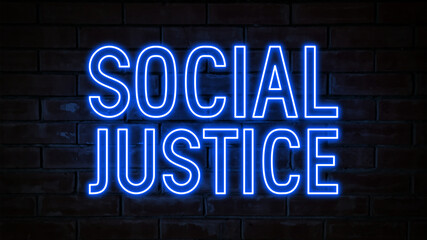 Social justice - blue neon light word on brick wall background