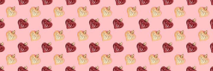 Pattern made of New Year decorations in heart shape on a pink background. Creative festive concept.