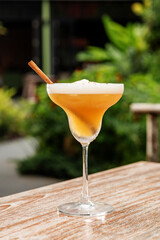 Fruit alcohol cocktail and cinnamon stick on the blurred background