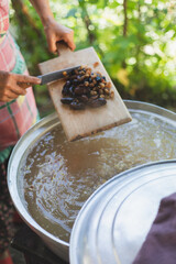 Young woman making turkish dessert (asure) in the kitchen.Cooking Traditional Dessert Asure,Ashura or Noah Pudding with stainless steel cookware on stove.Holding a ladle with ingredients in vapor 