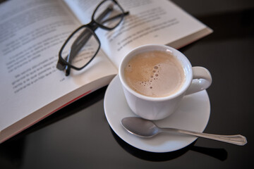 have a cup of coffee reading a book with glasses