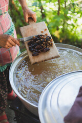 Young woman making turkish dessert (asure) in the kitchen.Cooking Traditional Dessert Asure,Ashura or Noah Pudding with stainless steel cookware on stove.Holding a ladle with ingredients in vapor 