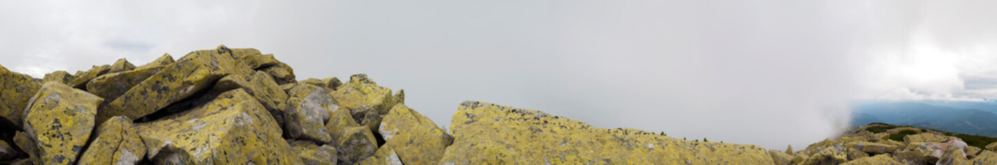 Panorama of mountain peaks. Panorama of rocky placers and storm clouds