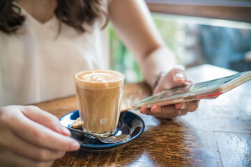 Women hand use smartphone drink hot latte coffee sitting in cafe