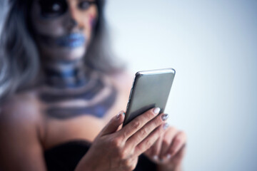 Spooky portrait of woman in halloween gotic makeup holding smartphone