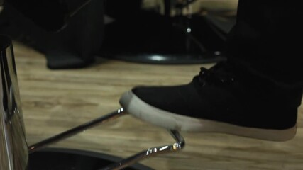Man adjusting a barber chair using his foot